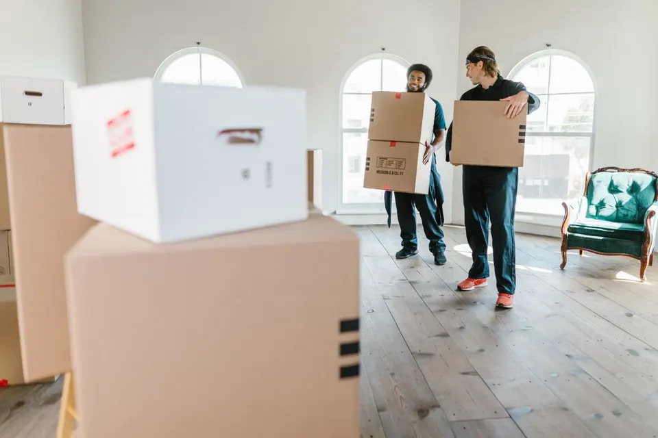 Movers carrying cardboard boxes inside a home